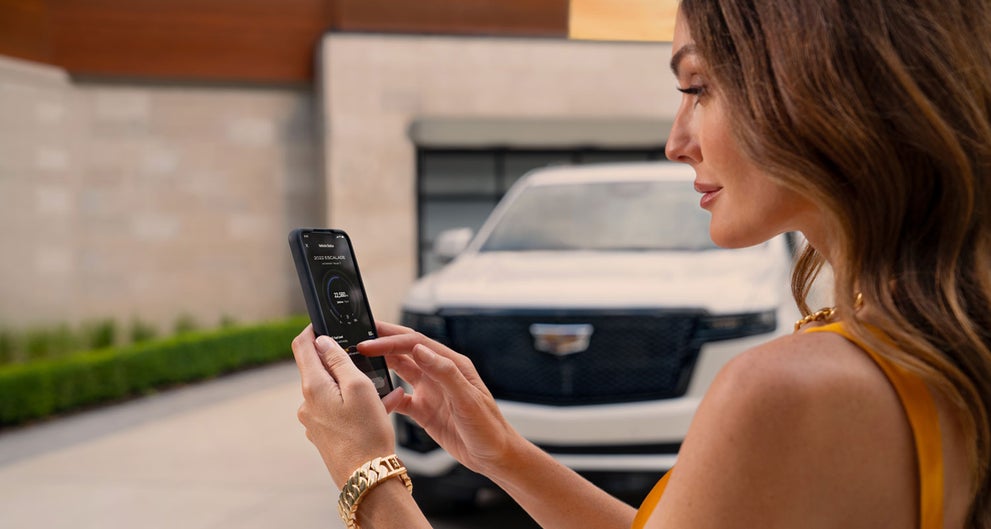 lady checking her mobile with a Cadillac vehicle background | Fitzgerald Cadillac of Hagerstown in Hagerstown MD