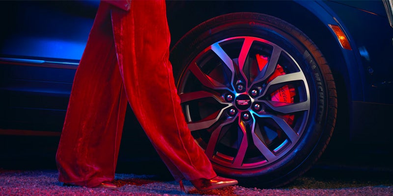 woman in red velvet pants passing Cadillac wheel closeup