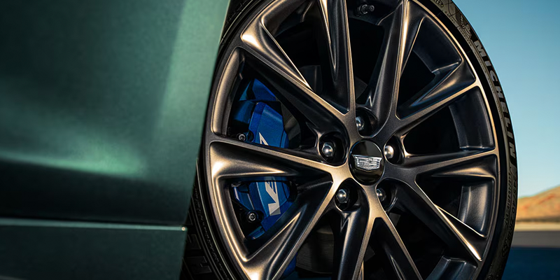 Close-up of a Cadillac alloy wheel with blue brake caliper.