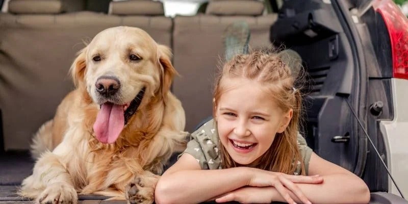 girl and her dog sitting in the back of a vehicle
